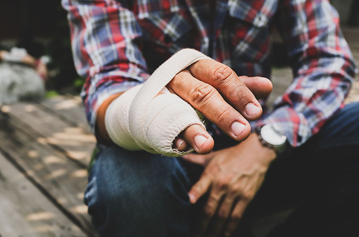 Person wearing a plaid shirt with a heavily bandaged hand, illustrating DIY medical treatments gone wrong.