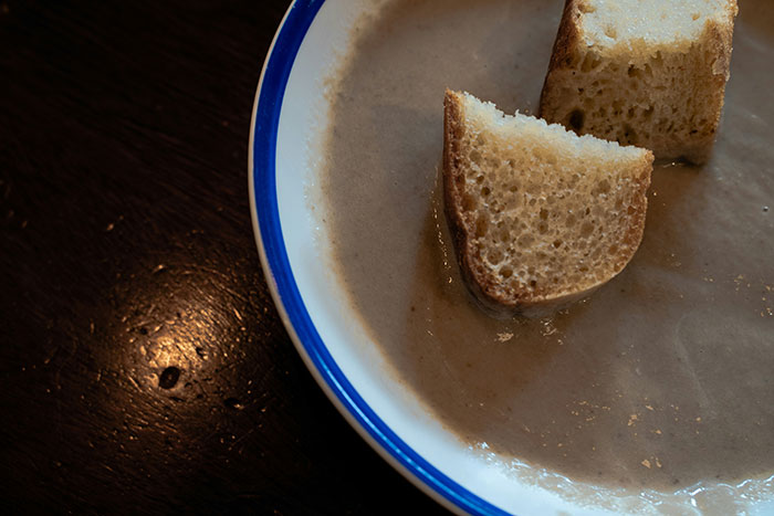 Bowl of thick homemade soup with two pieces of bread, illustrating DIY medical treatments gone wrong.
