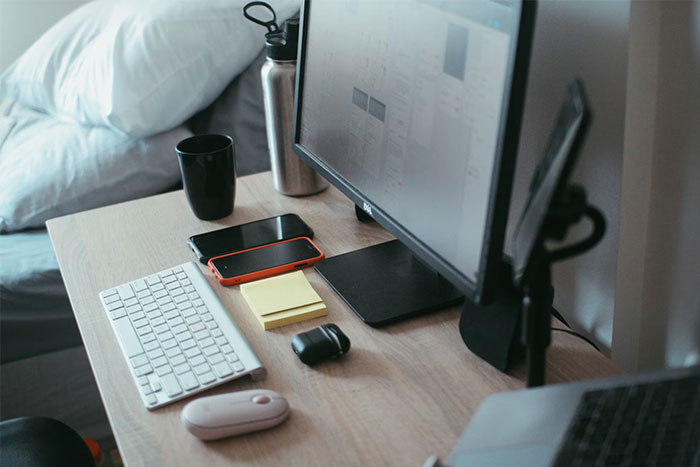 Work desk setup in strangers’ homes with computer, keyboard, smartphone, and personal items sharing unforgettable views.