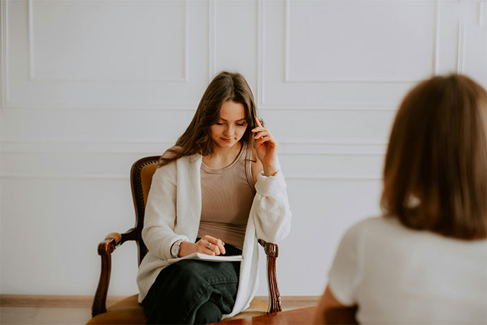 Woman taking notes during an interview, illustrating stories from people who work in strangers’ homes.