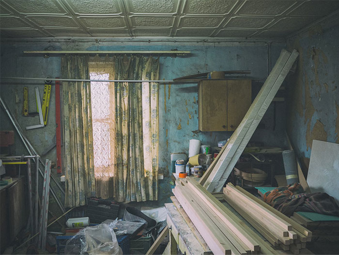 Cluttered, worn home workshop with construction wood and tools, showing unforgettable scenes seen by people working in strangers’ homes.