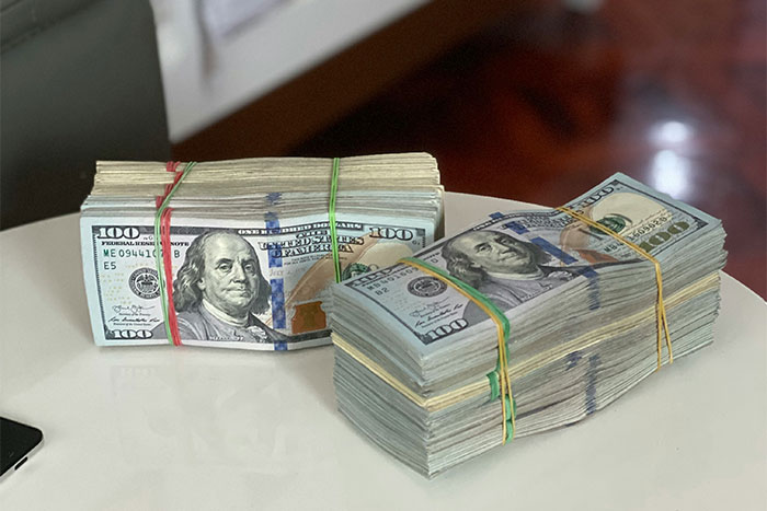 Stacks of hundred-dollar bills on a table representing unforgettable things seen inside strangers’ homes by workers.