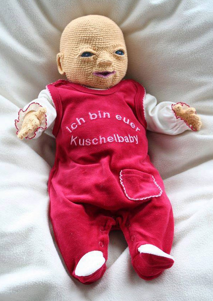 Crocheted creepy baby doll with unsettling facial features wearing a red outfit, part of creepy discoveries shared online.
