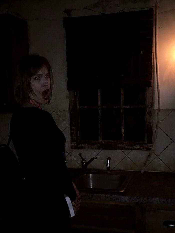 Woman in a dark room showing a scared face near an old sink with a creepy atmosphere at night
