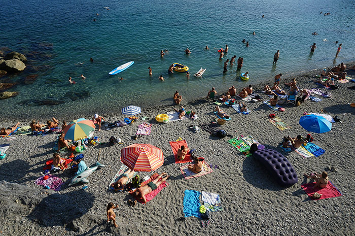 Crowded beach scene showing people sunbathing and swimming, illustrating mind-blowing cultural differences in leisure activities.