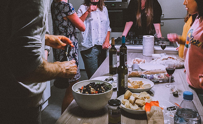 Group of people enjoying food and wine, illustrating cultural differences and diverse social dining traditions.