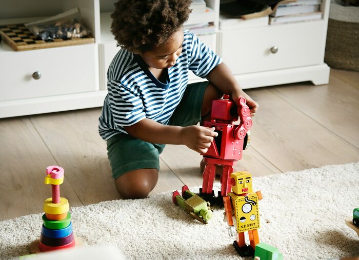 Young child playing with vintage-style toy robots on the floor, illustrating classic boomer opinions and nostalgia.