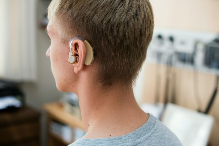 Young person wearing a hearing aid, demonstrating how good or bad genes can affect hearing ability.