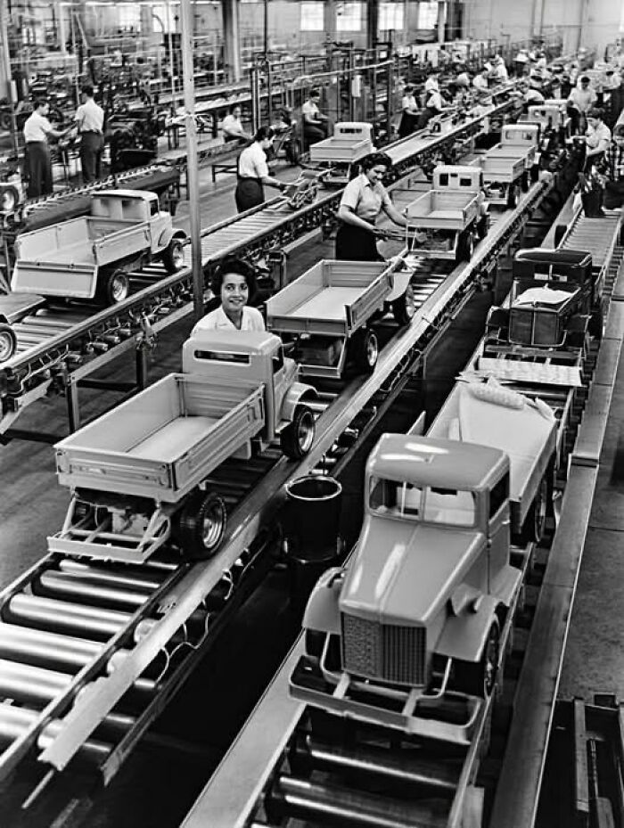 Women assembling toy trucks on a factory line, illustrating unusual and interesting facts from historical manufacturing events.