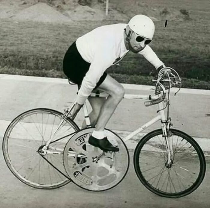 Man in helmet and sunglasses riding a vintage racing bicycle showcasing unusual and wonderful cycling gear.