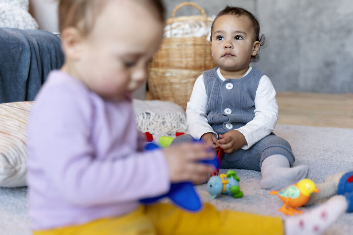 Two toddlers playing with toys on the floor, illustrating hilariously bad names that had parents questioned.