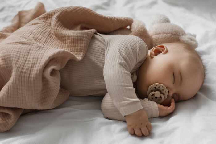 Sleeping baby covered with a brown blanket, illustrating hilariously bad names that had people questioning parenting choices.