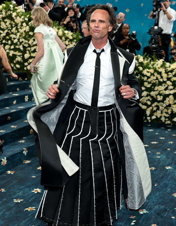 Man wearing a black and white stitched outfit posing on a floral carpet at the biggest fashion fails Met Gala 2025 event.