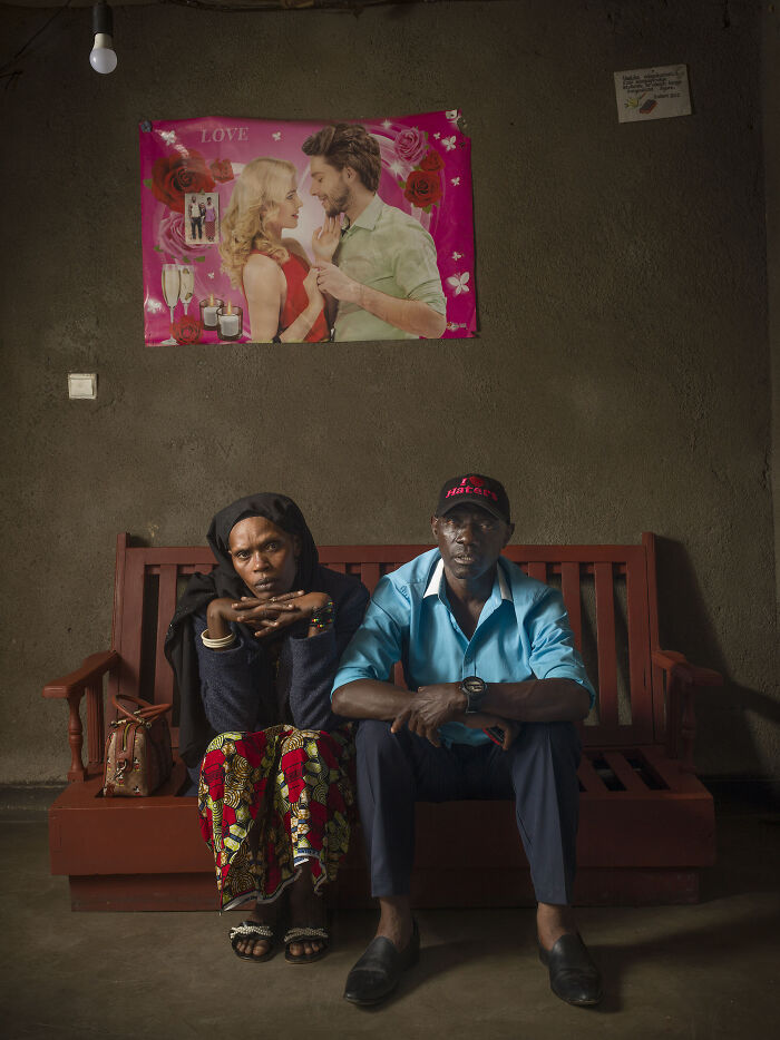 Couple sitting on a wooden bench indoors, capturing raw emotion and the essence of humanity in a simple room.
