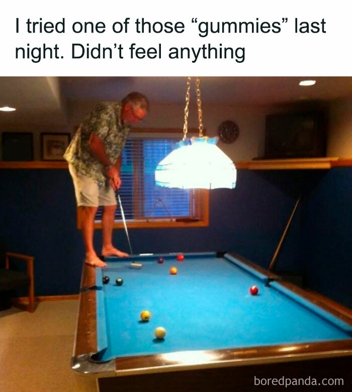 Man playing pool barefoot on the table in a dimly lit room, capturing hilariously silly jokes and peak dad humor.