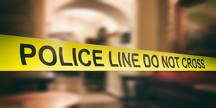 Yellow police line tape blocking access in a blurred indoor crime scene related to fatal beating incident.