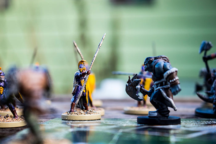 Miniature wargaming studio setup with detailed figurines engaged in a battle scene on a tabletop game board.