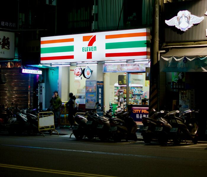 7-Eleven convenience store at night with scooters parked outside, illustrating a company secret you can share now.