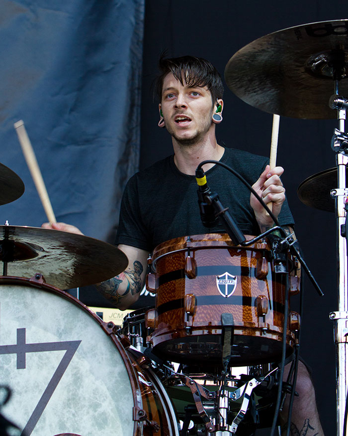 Famous drummer performing on stage, playing drums with intense focus during a live music event.