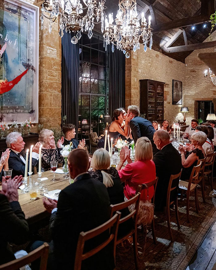 Guests seated at a long dining table with candles during David Beckham's 50th birthday party amid family tension.