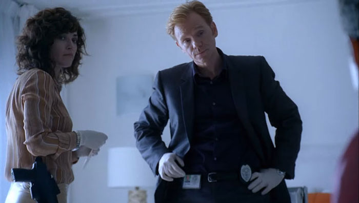 David Caruso as the coolest TV cop wearing gloves and badge, engaged in a serious investigation scene.