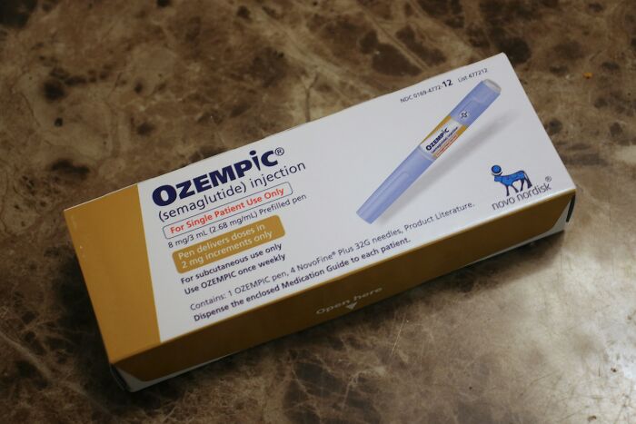 Ozempic injection pen box on a marble surface, related to Ozempic teeth side effects from weight loss medications.