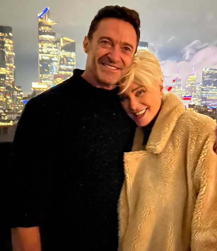 Hugh Jackman and Deborra-Lee Furness smiling together outdoors with city lights in the background at night.