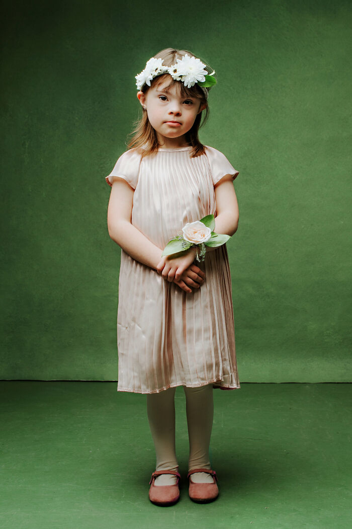 Young girl with Down syndrome wearing a flower crown and holding a corsage, symbolizing inclusion and celebration.