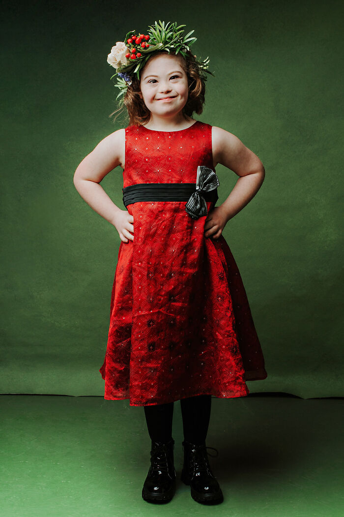 Young girl with Down syndrome wearing a red dress and floral crown, celebrating inclusion and changing perceptions.