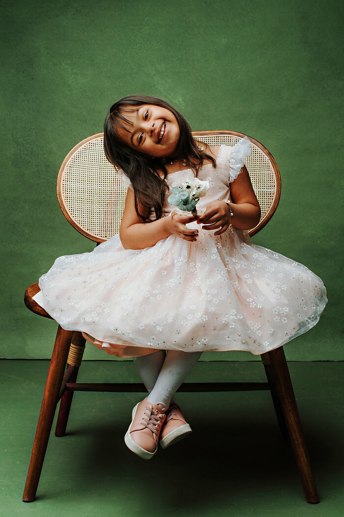 Young girl with Down syndrome smiling in a white dress, celebrating inclusion and changing perceptions through photography.