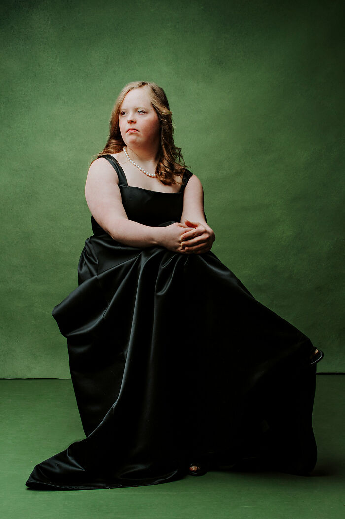 Young woman with Down syndrome in black dress and pearl necklace, symbolizing inclusion and changing perceptions.