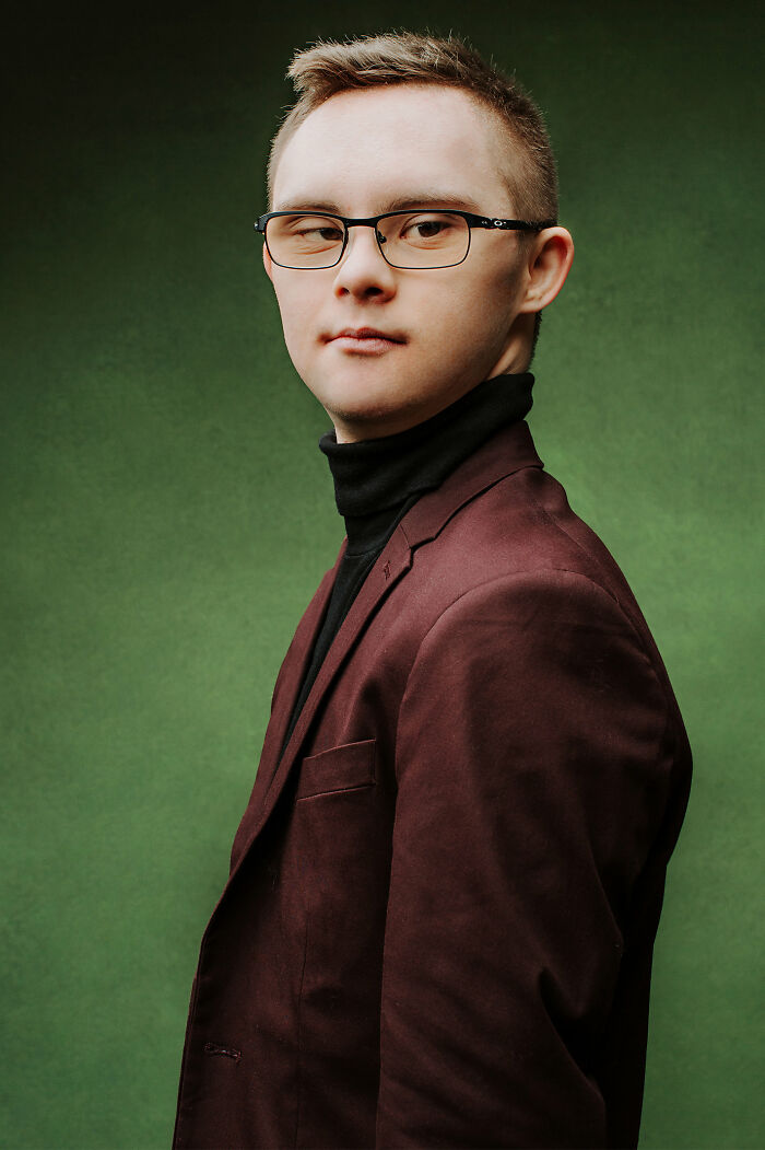 Young man with Down syndrome wearing glasses and a burgundy jacket, representing inclusion and changing perception.