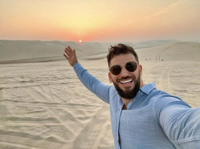 Actor who played Viktor Krum from Harry Potter smiling and taking a selfie in a desert during sunset.