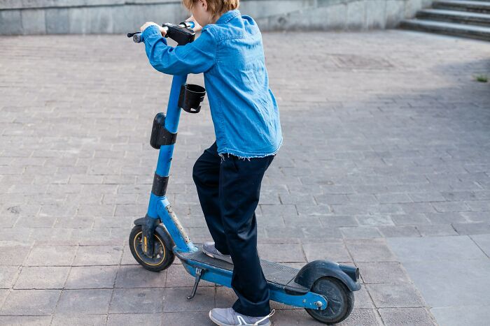 Child wearing a blue jacket riding a blue electric scooter outdoors, illustrating modern boomer opinions on mobility trends.