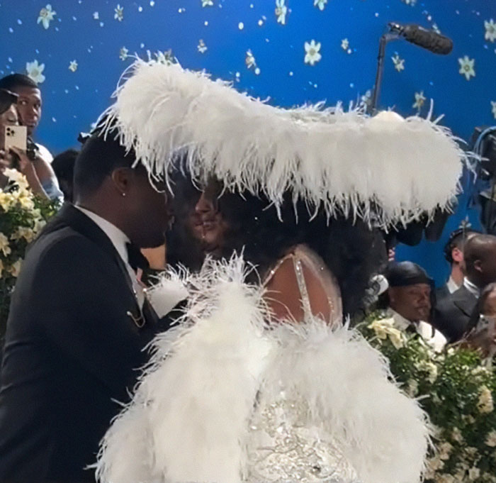 Zendaya reacting with surprise as Diana Ross in a white feathered outfit upstages her at the Met Gala red carpet event.