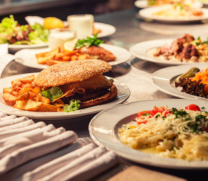 Close-up of various plated meals on a table with a burger and fries, unrelated to Ozempic tongue side effect.