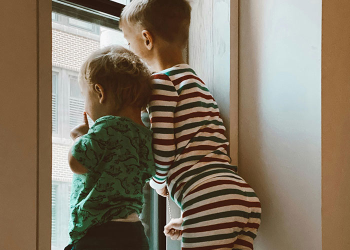 Two young children in striped and patterned pajamas looking out a window, reflecting on dark family secrets in adulthood.
