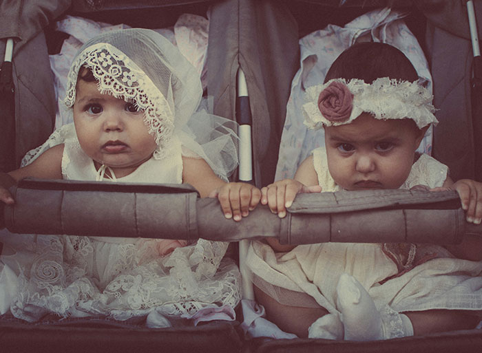 Two babies in vintage lace outfits sitting side by side, evoking dark family secrets in childhood memories.