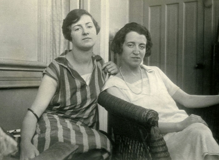 Two women sitting closely in a vintage setting, reflecting on dark family secrets that made sense in adulthood.