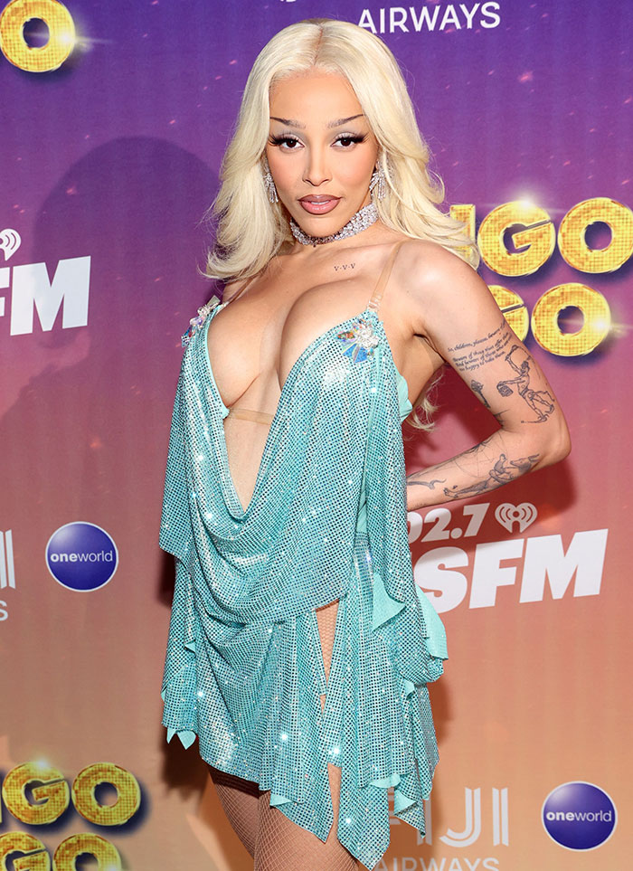Doja Cat on red carpet in sparkling blue dress, showing tattoos and glamorous makeup after plastic surgery mishap. Doja Cat on red carpet in sparkling blue dress, showing tattoos and glamorous makeup after plastic surgery mishap.