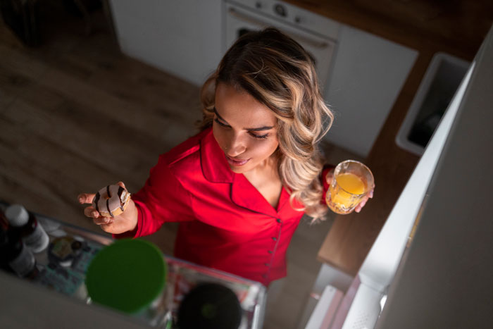 Young woman in red shirt holding a drink and snack, highlighting a student spiking drinks with sleep aids scenario.