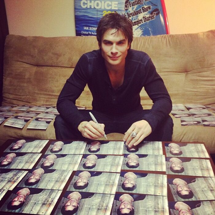 Celebrity signing multiple photos while seated on a couch, a nostalgic Instagram post from way back in the day.