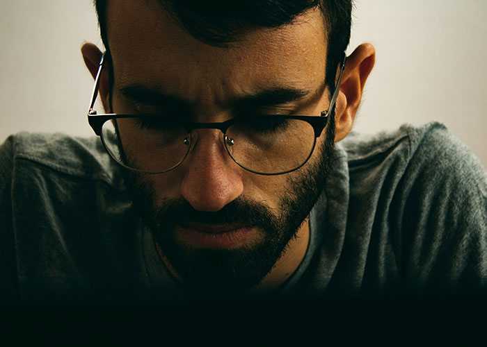 Man with glasses looking down pensively, illustrating a man admitting he found wife repulsive on first date.