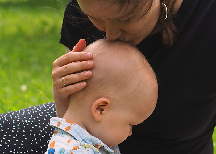Woman showing affection to a child outdoors, illustrating themes of relationship and emotional complexity in a personal setting.