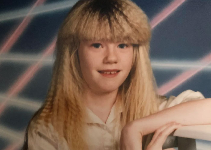 Young person with crimped hair and bangs posing for a retro photo reflecting popular fads from past decades.