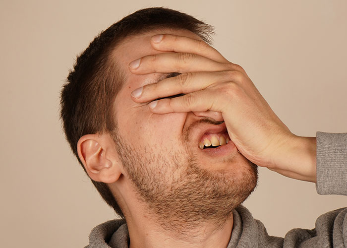 Man covering his face with hand in frustration, reflecting on the dumbest fad he participated in.