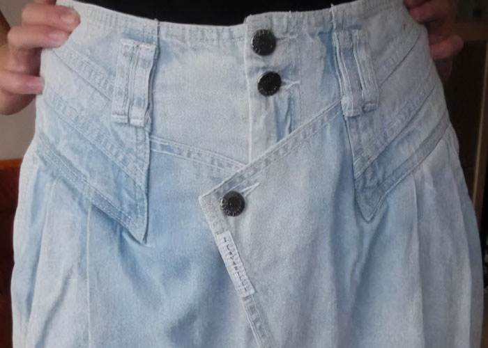 Hands holding a vintage acid-wash denim skirt, representing a dumbest fad people participated in from the 90s.