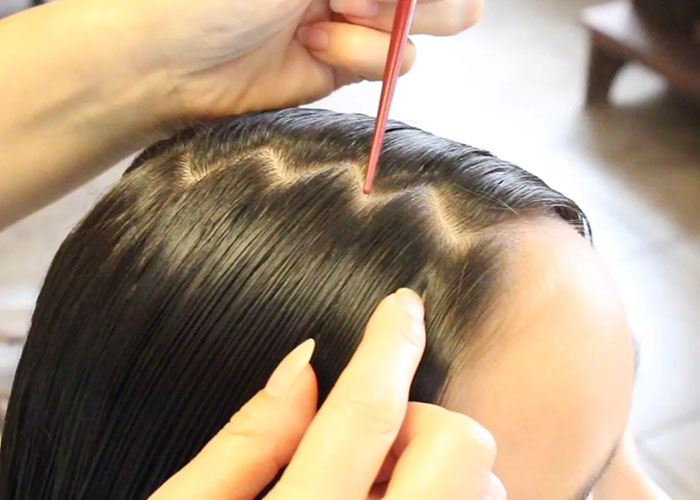 Hands parting wet hair with a comb, illustrating a common dumb fad hairstyle trend from past decades.