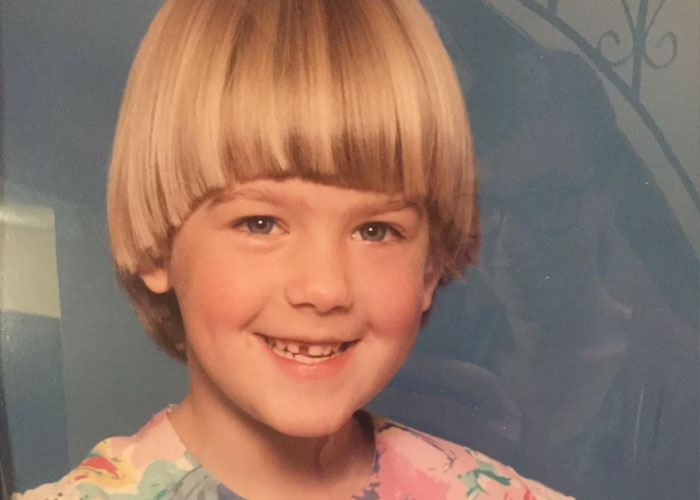 Young child with a bowl haircut smiling in a colorful shirt, illustrating a dumb fad hairstyle from past decades.