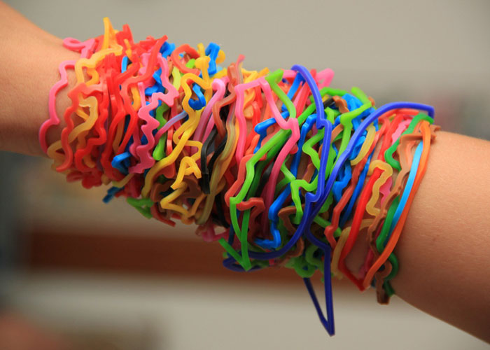 Colorful plastic bracelets stacked on wrist representing a popular dumb fad people participated in.